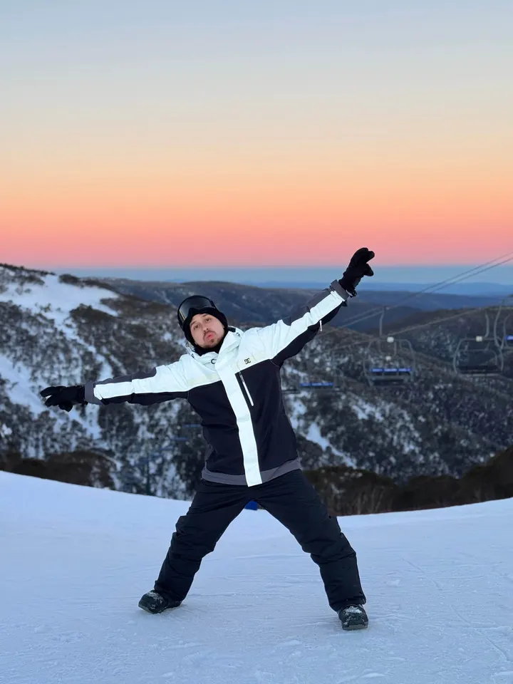 Andres with open arms in the snow at sunset